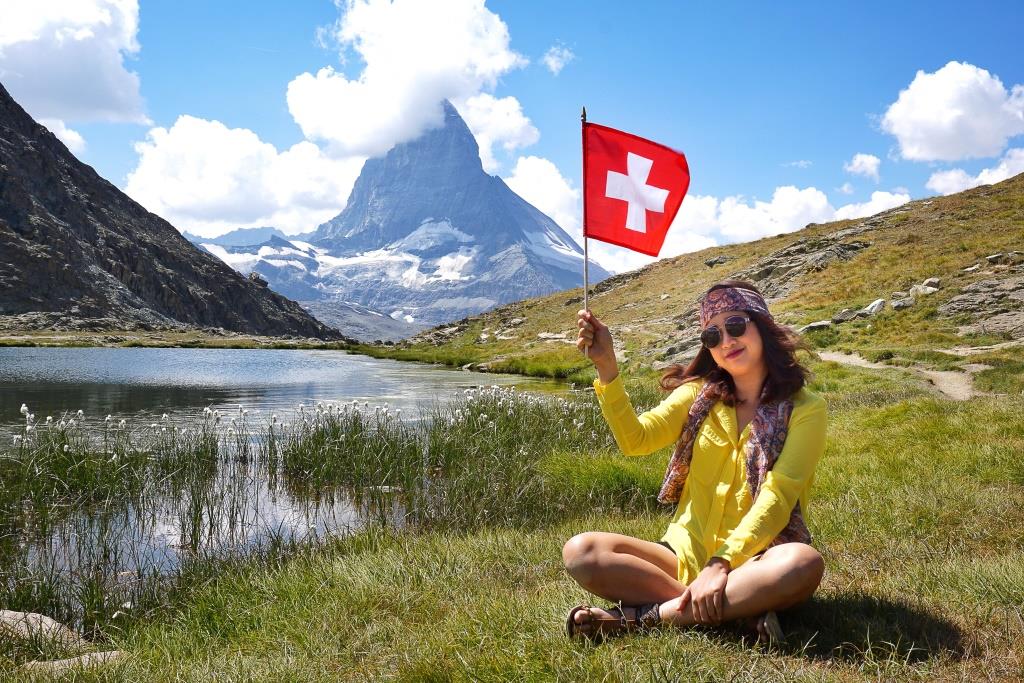 スイス国旗を持つ女性とマッターホルン